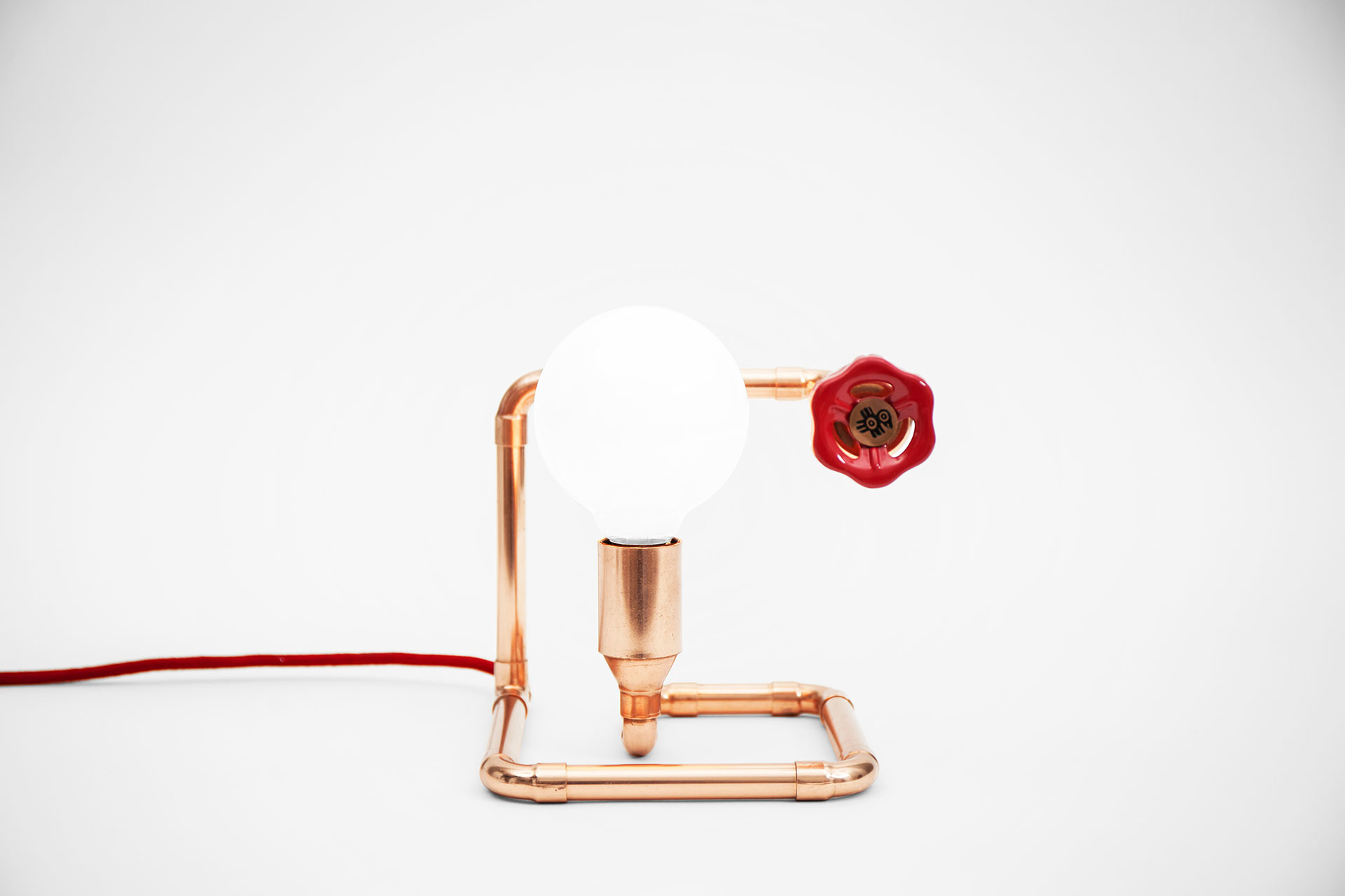 Simple bedside lamp in trendy copper color with red knob dimmer and red braided cord in minimalist style