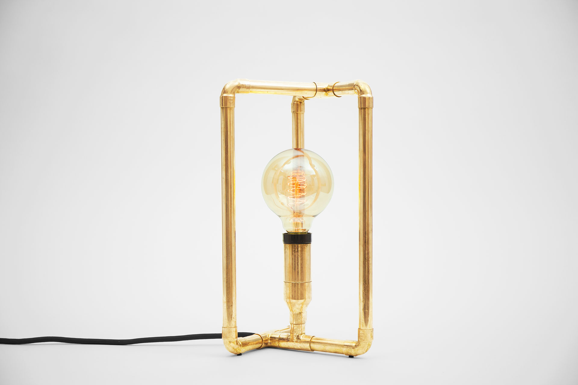 Small bedside lamp in gold brass metal finish with retro Tesla bulb inspired by modern minimalist design
