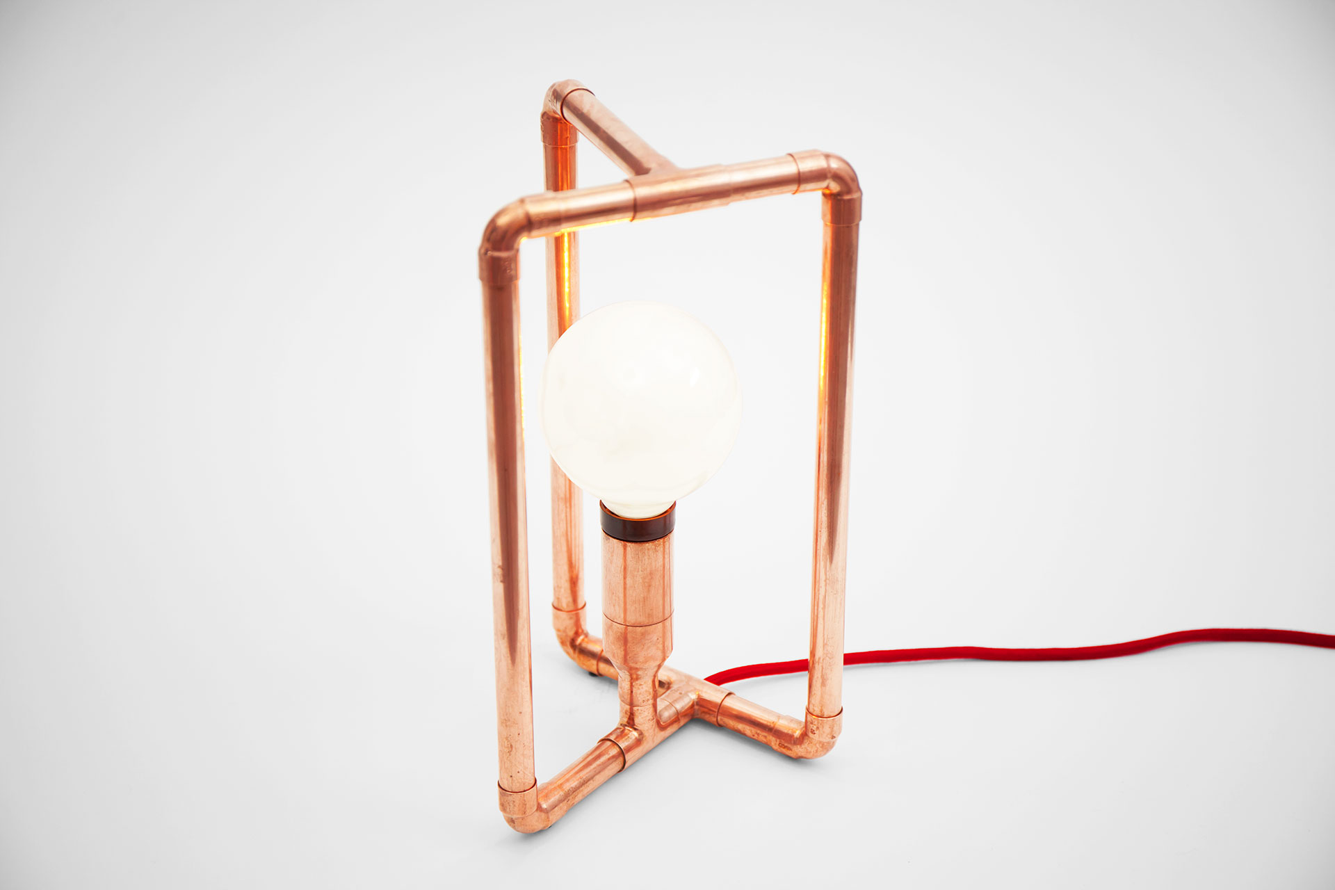 Geometric design desk lamp made of copper tubing with red braided cord inspired by 3D Möbius strip