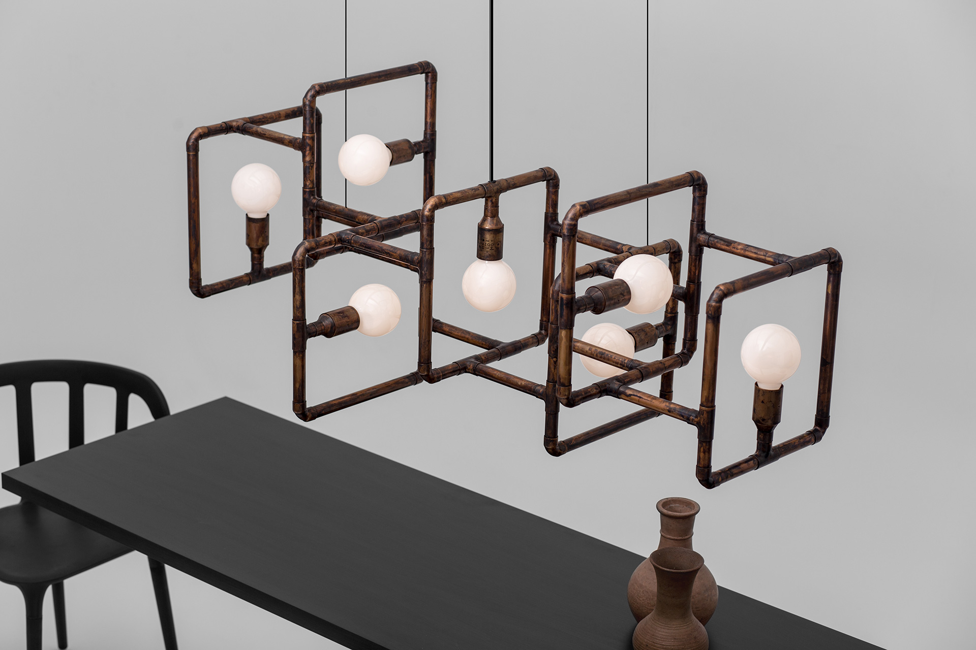 Industrial chandelier in aged copper metal finish made by european lighting design studio in modern loft interior